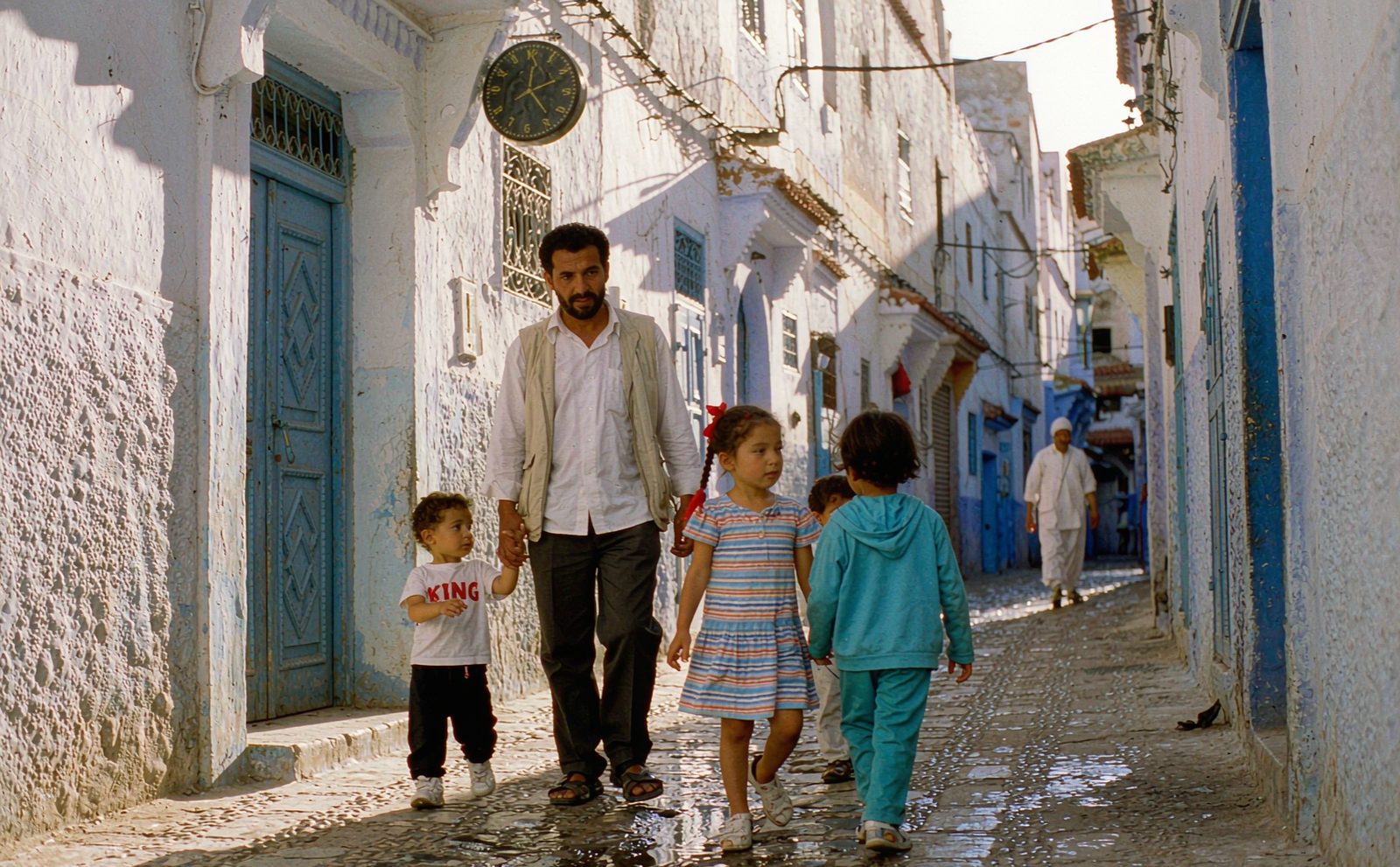 A Muslim family with two young children walking through a sunlit historic medina street