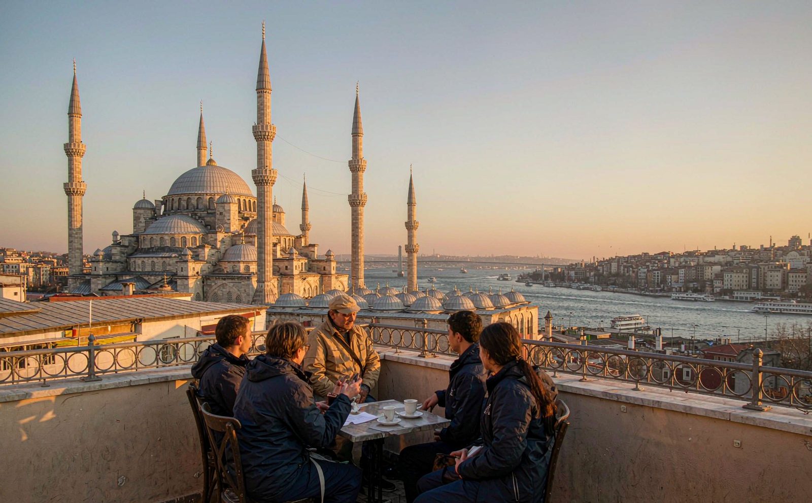 A small group of travellers crossing a stone square between two Ottoman mosques in Istanbul at golden hour