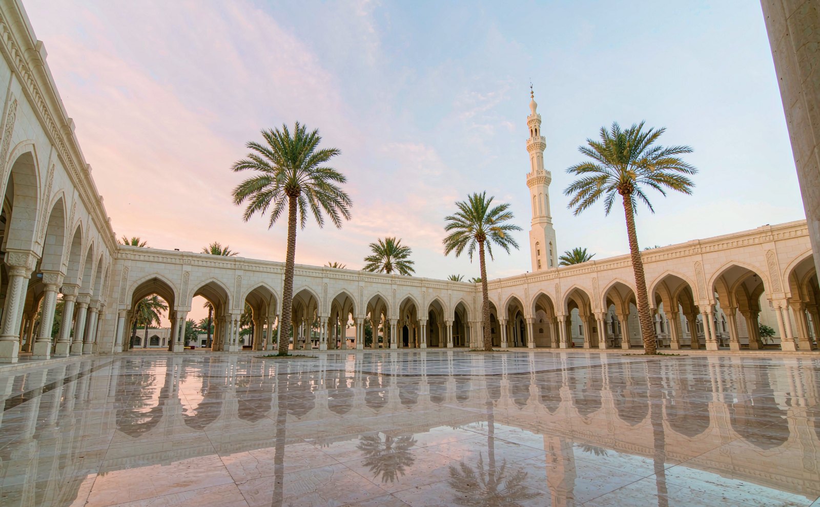 A serene mosque courtyard at dawn, arcades and palm trees reflected in polished marble